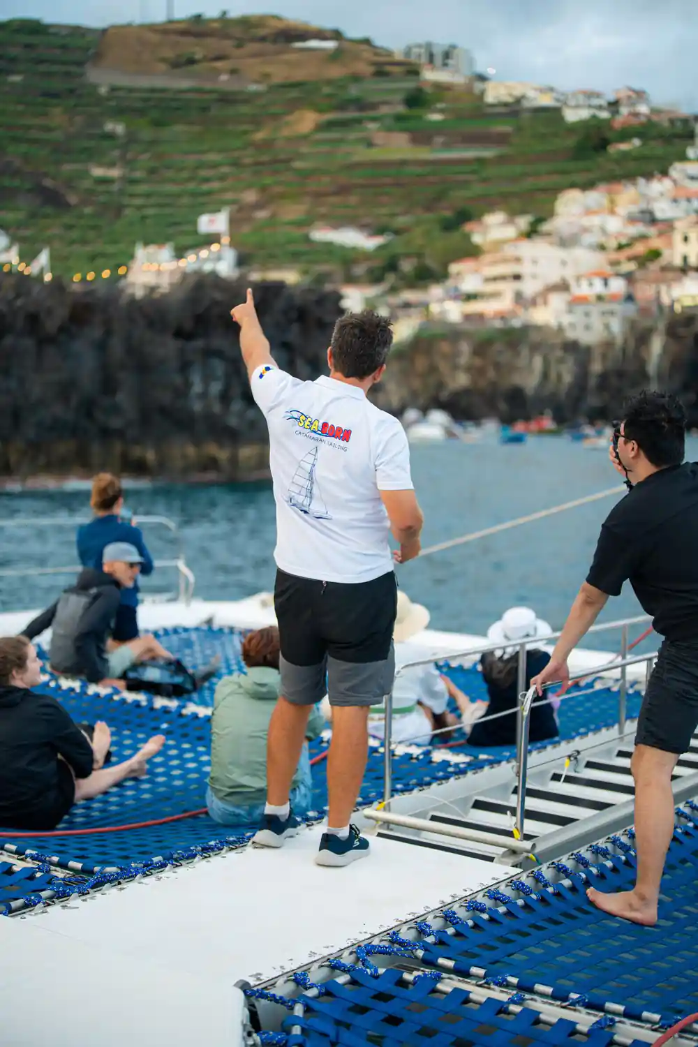 A crew member pointing out something to guests from the foredeck