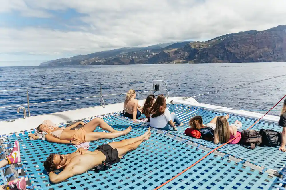 Guests lying on the blue mesh nets with the coast behind