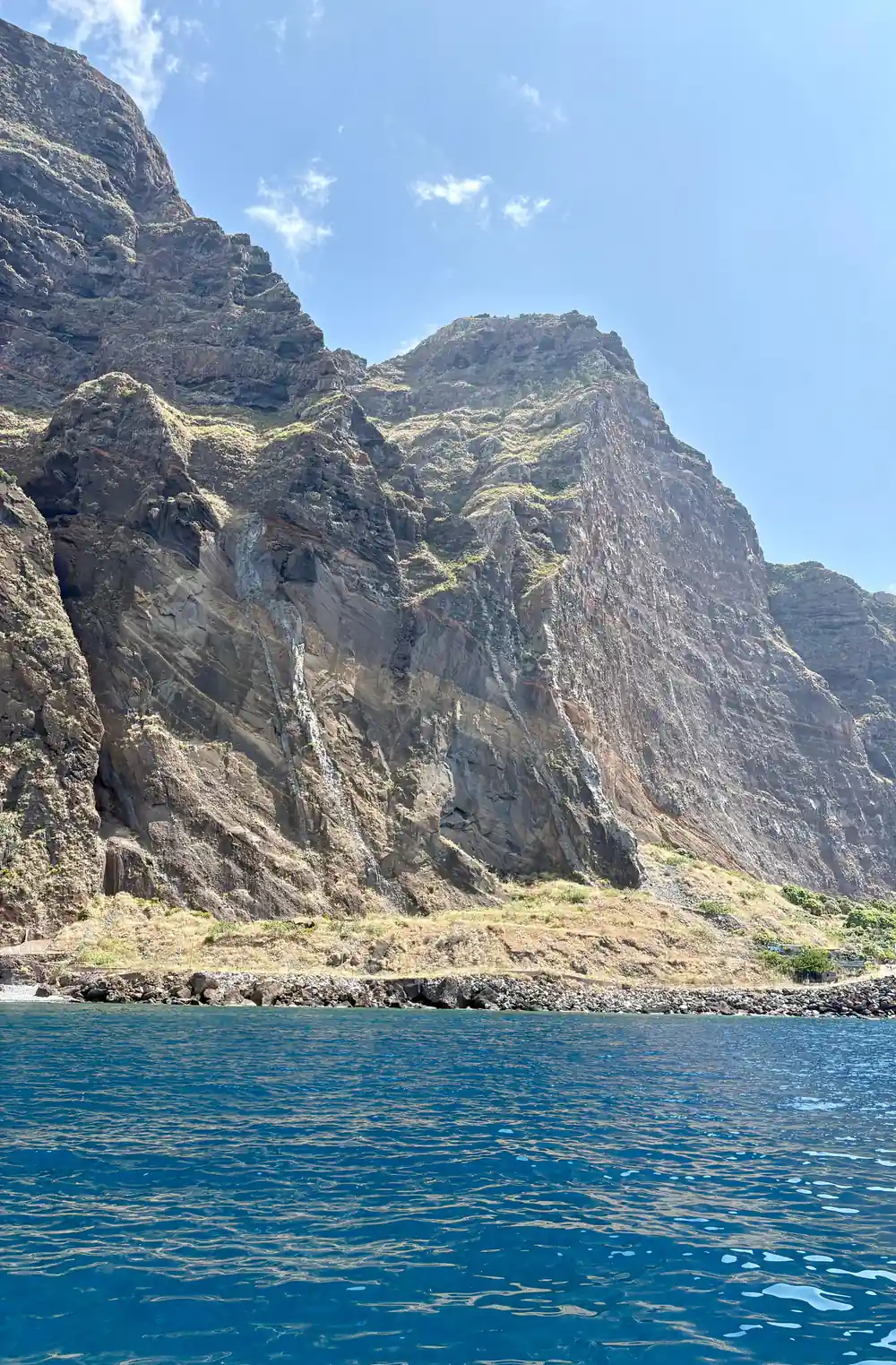 A jagged rock headland dropping into clear green water