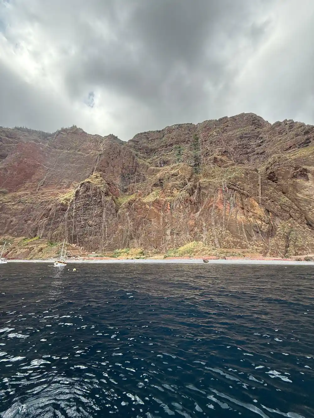 A rugged cliff and shoreline with a boat beneath it