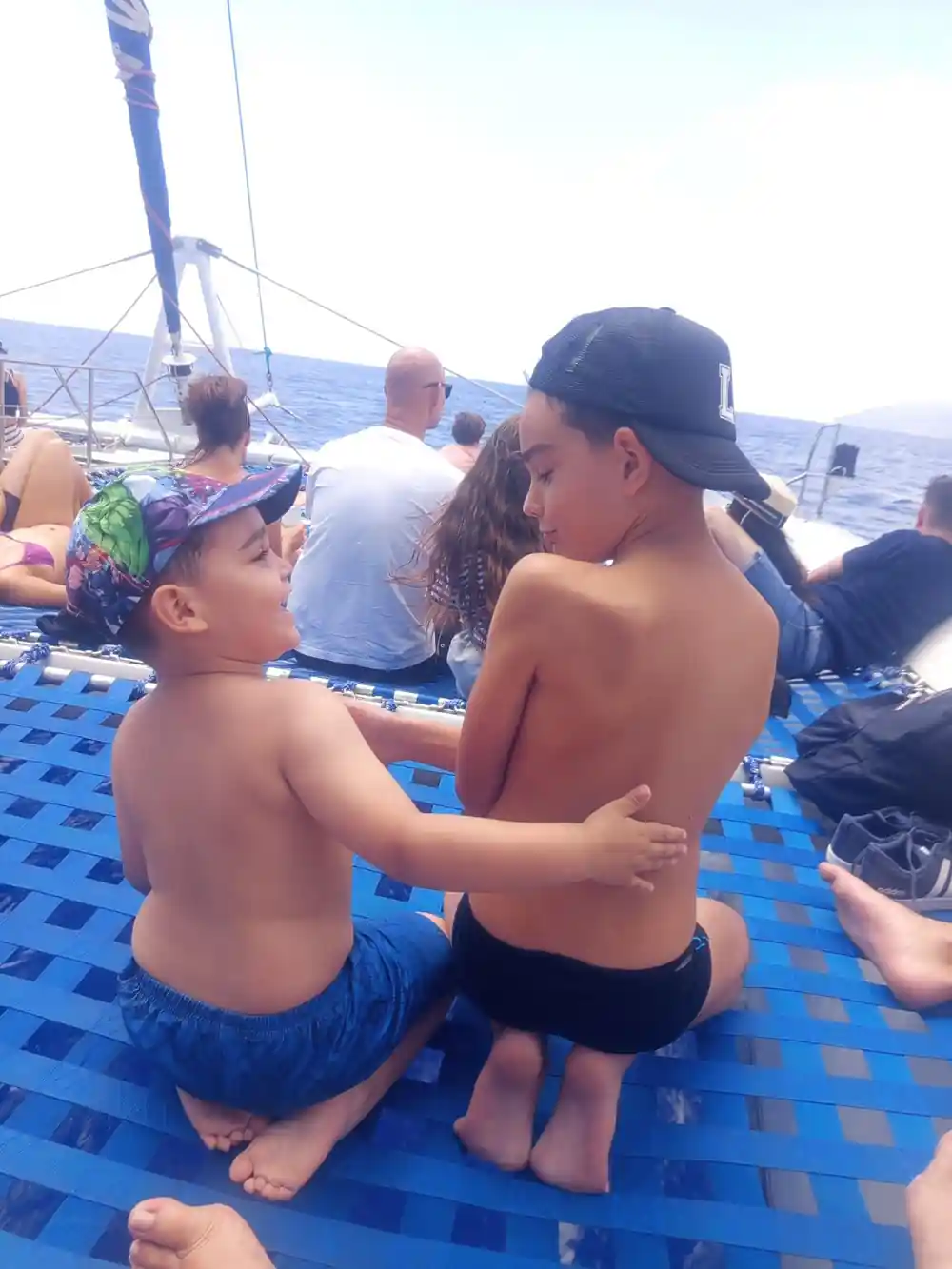 Two boys sitting together on the blue deck nets