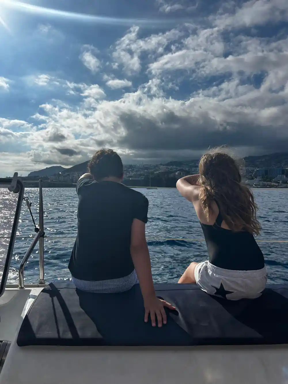 Two guests sitting on the bow watching the coastline