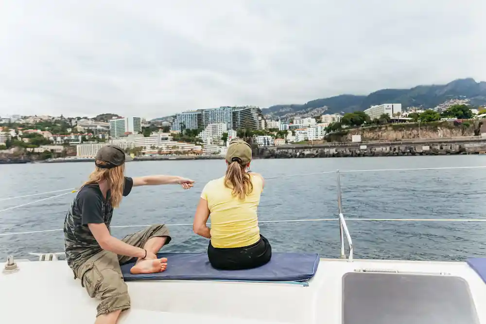 Two guests sitting on deck looking toward the Funchal shoreline