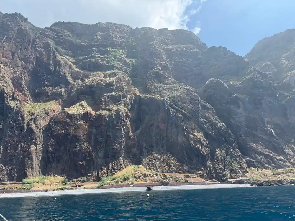 A vast layered cliff face rising straight from the sea